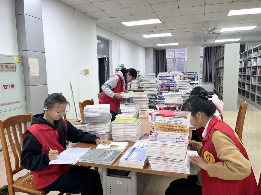 志愿者们在学校图书馆为新书编码、登记入库